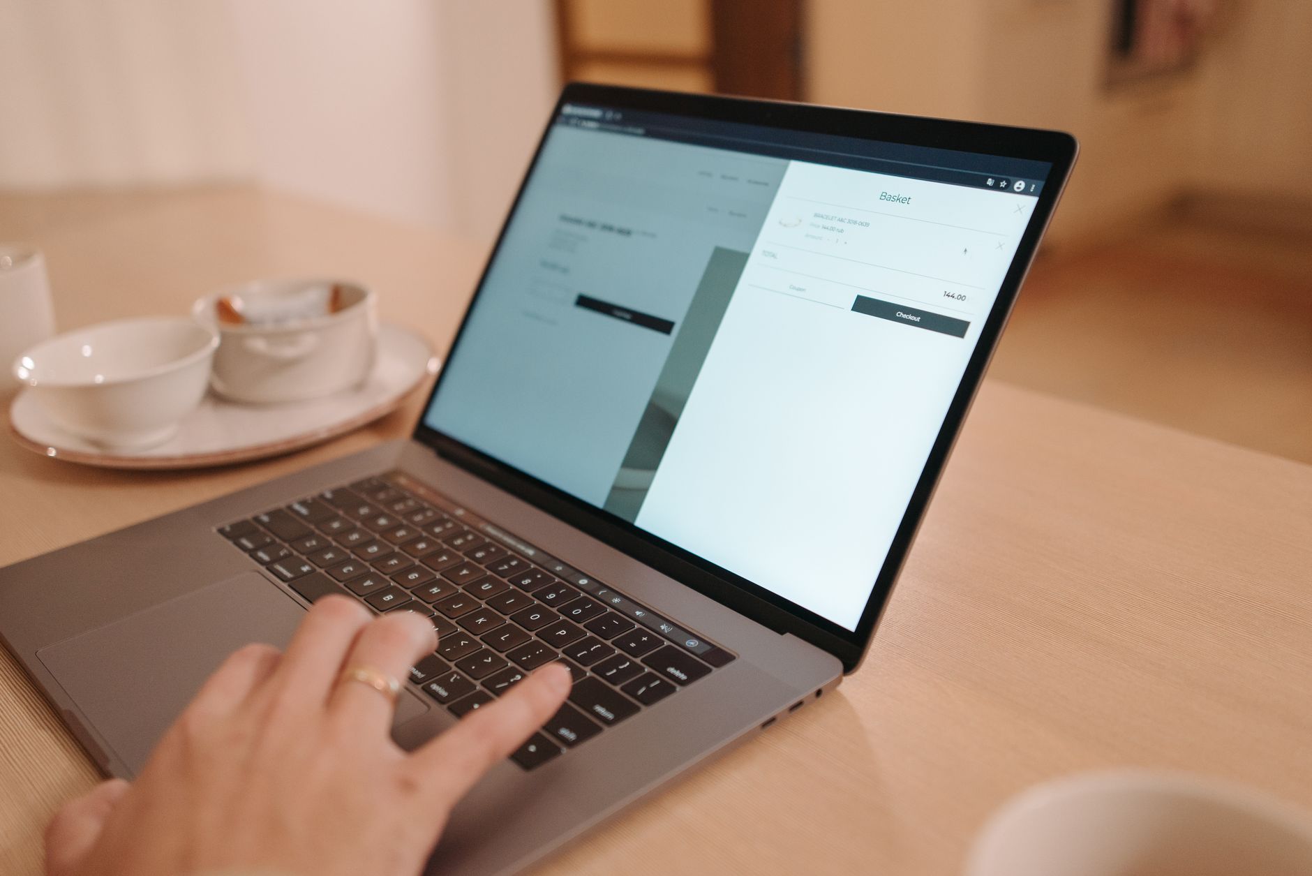 Primo piano di una persona che usa un laptop su un tavolo di legno, in un'atmosfera calda.
